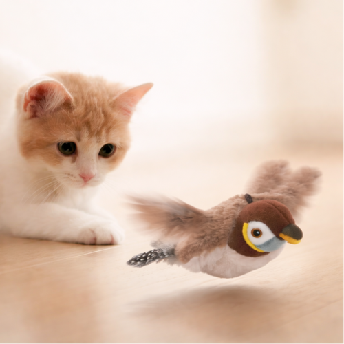 Cat playing with a bird-shaped toy on a light surface
